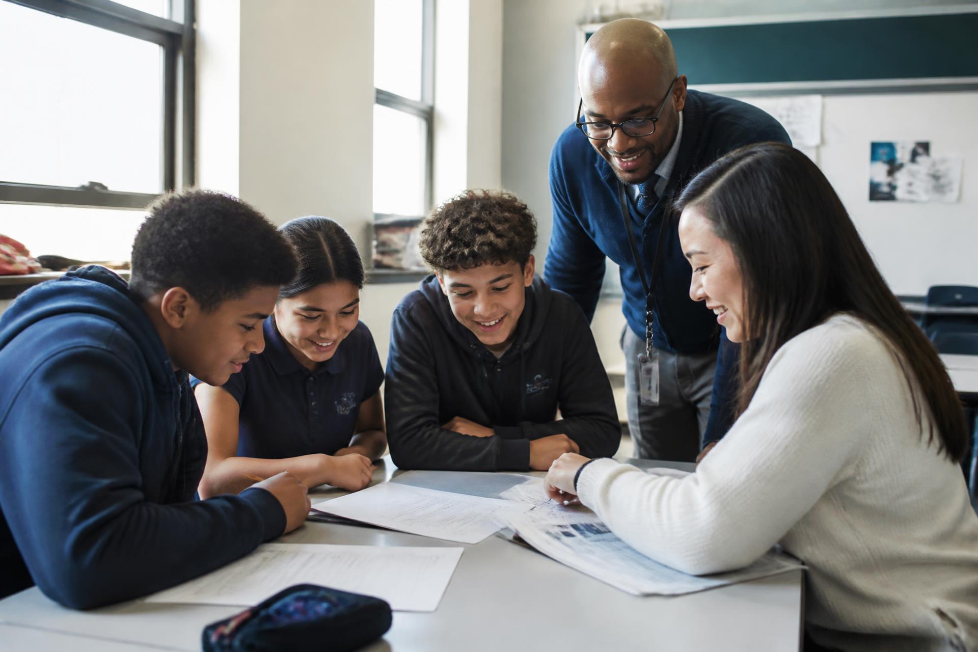 Educators and students reviewing student work together around a classroom table